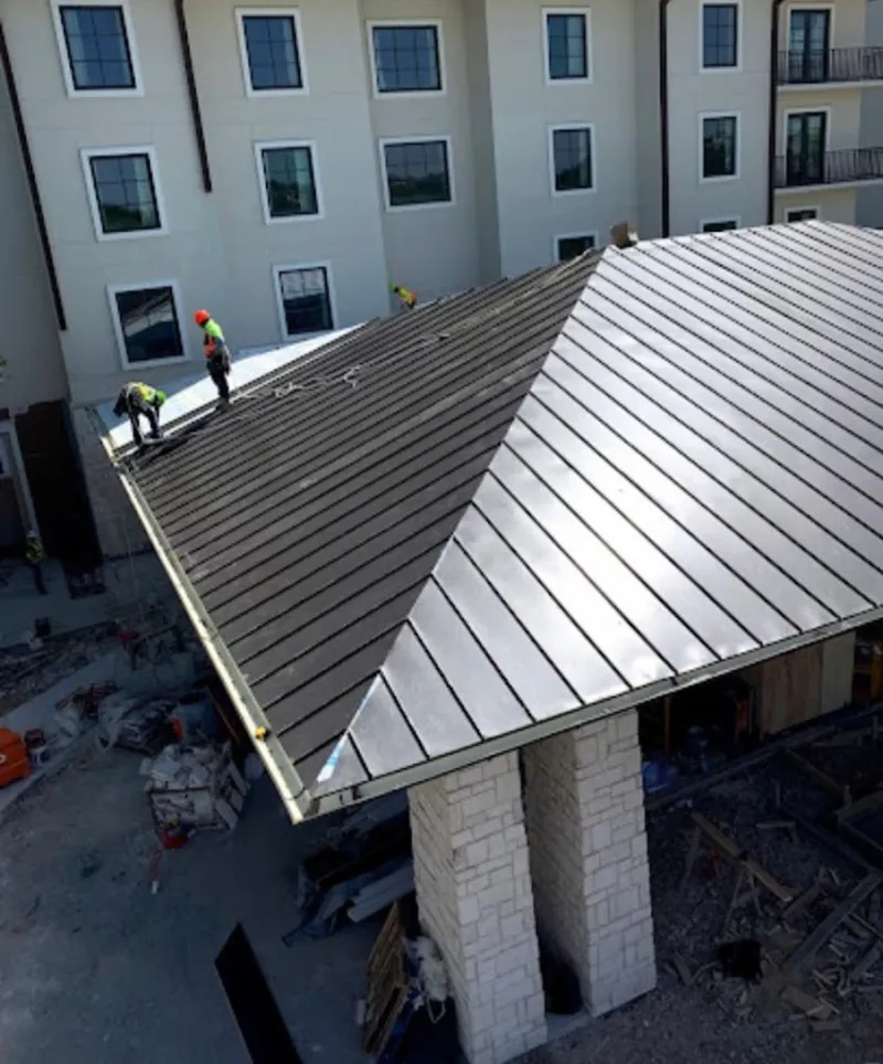 Crew installing standing seam metal roof panels on a commercial project in Peabody
